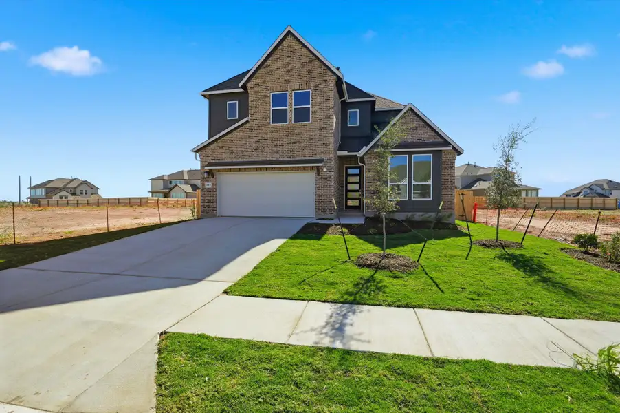 View of front facade with an attached garage, concrete driveway, and brick siding