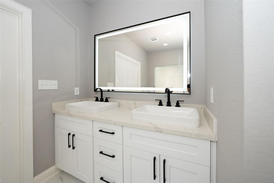 This stylish bathroom features a beautiful double sink, offering both elegance and convenience, paired with a sleek modern mirror that enhances the bright, airy feel. Thoughtfully designed for comfort and functionality, this bathroom provides a serene retreat where you can refresh and unwind in style.