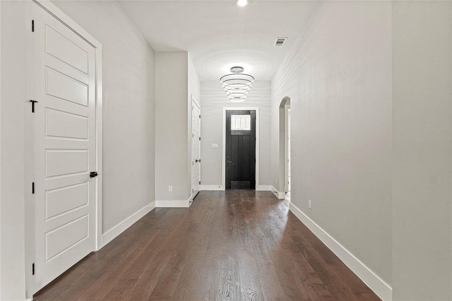 Foyer entrance with arched walkways and dark wood-style floors