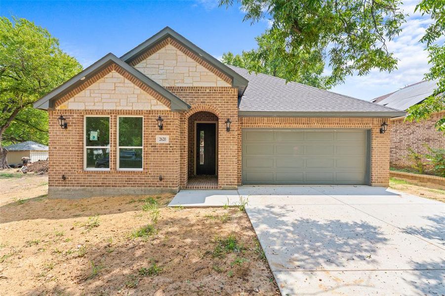 View of front of home featuring driveway, brick siding, a garage, and a shingled roof