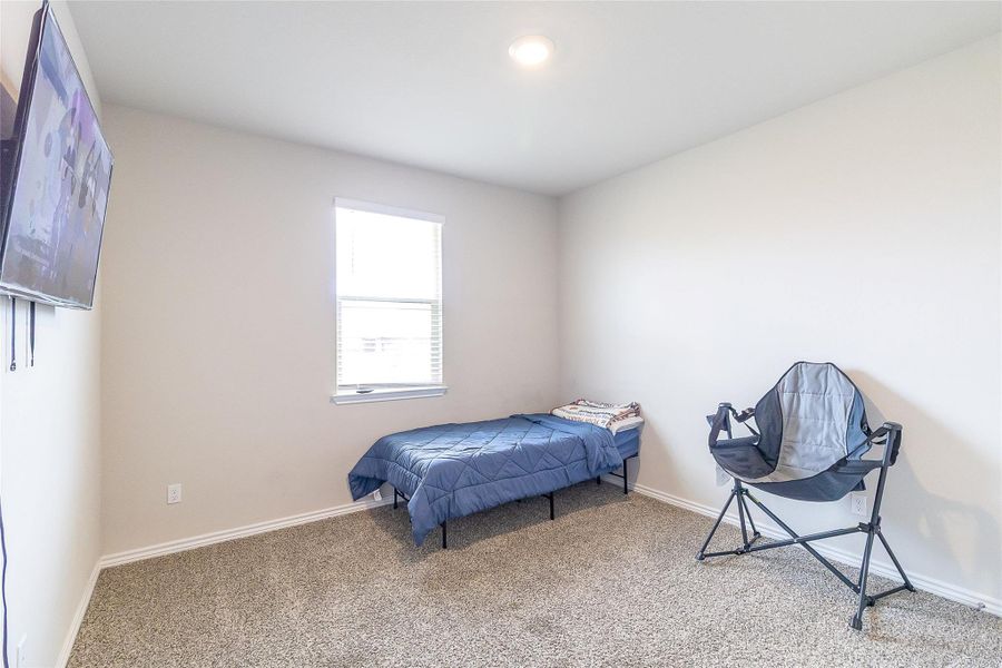 A quiet bedroom offers plush carpeting and a sun-filled window for serene comfort.