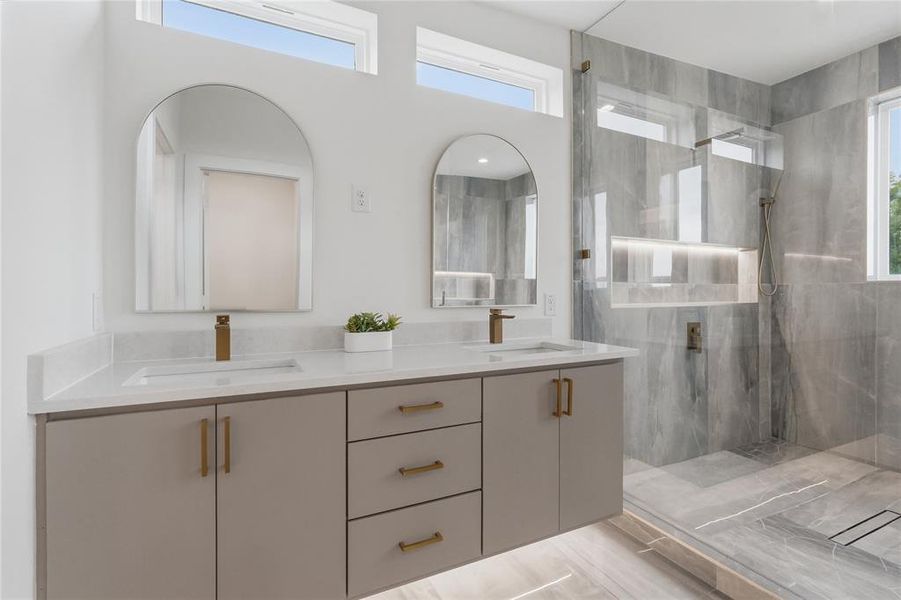 Dual vanity with quartz countertops and integrated sinks, complemented by arched mirrors and brass-finish fixtures Dual vanity with quartz countertops and integrated sinks, complemented by arched mirrors and brass-finish fixtures