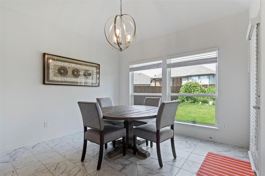 Dining space featuring marble look tile flooring and a chandelier