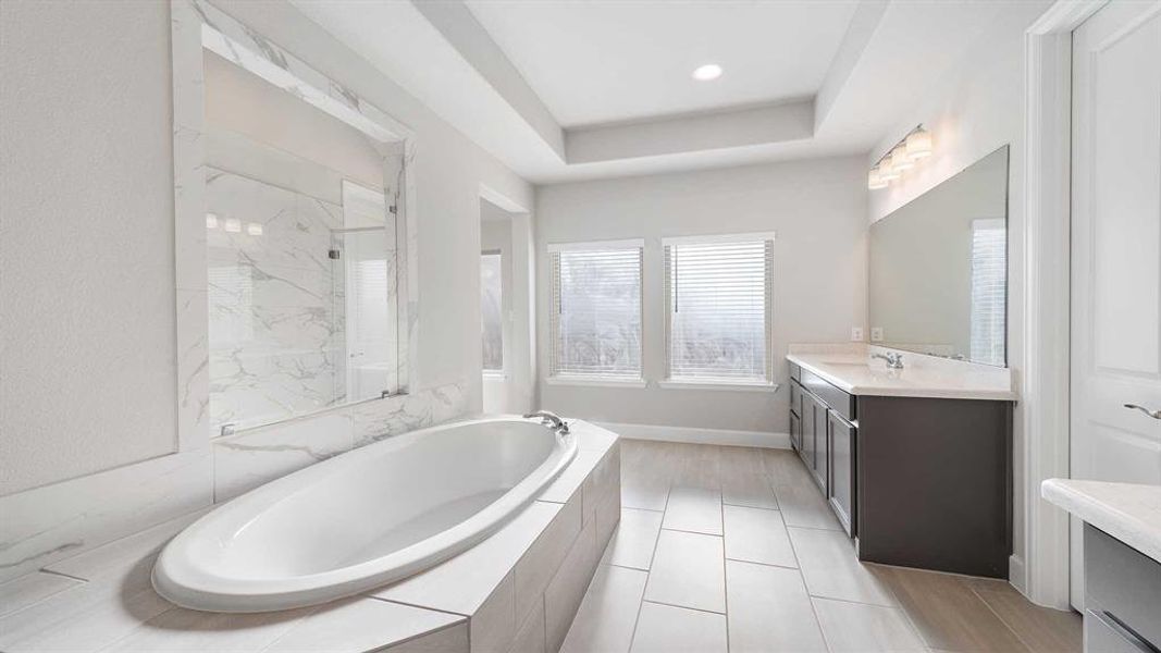 Bathroom featuring tile patterned floors, vanity, and plus walk in shower