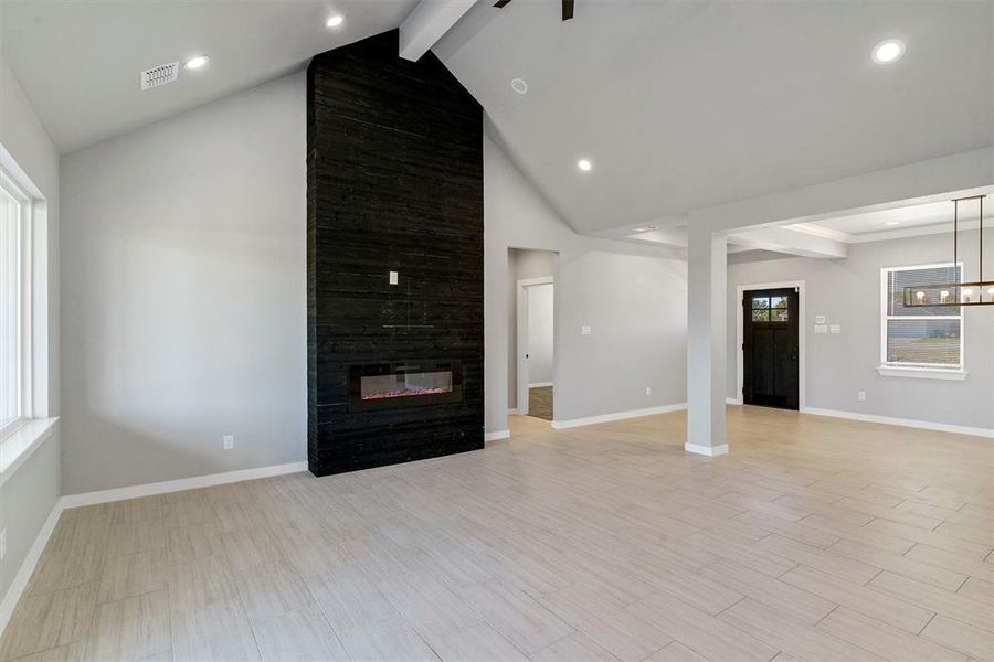 Unfurnished living room with a fireplace, light hardwood / wood-style flooring, and beamed ceiling