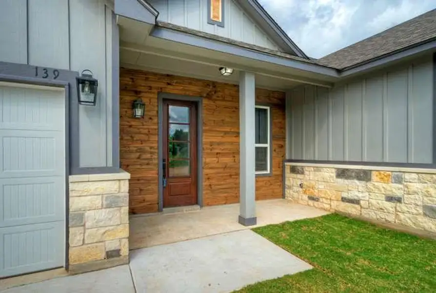 A welcoming entry features natural wood siding and sturdy stone accents.