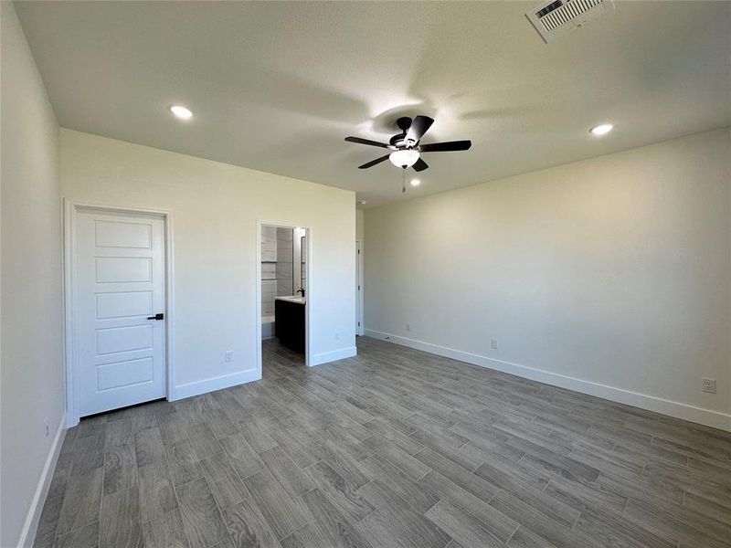 Unfurnished bedroom with ceiling fan, hardwood / wood-style floors, and connected bathroom