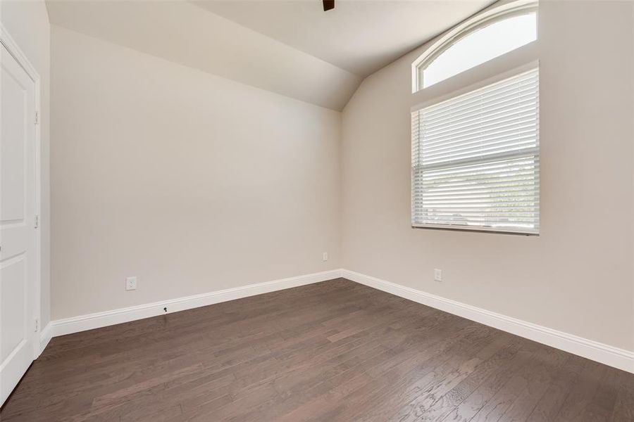 Unfurnished room featuring dark wood-style floors and vaulted ceiling Unfurnished room featuring dark wood-style floors and vaulted ceiling