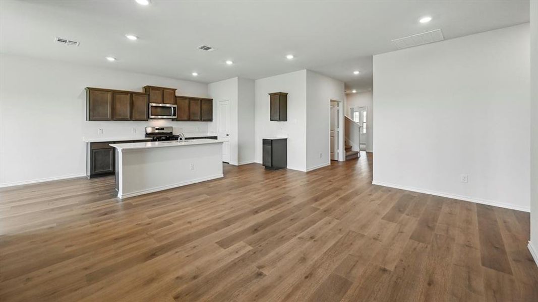 Kitchen with recessed lighting, light countertops, open floor plan, a kitchen island with sink, and stainless steel appliances