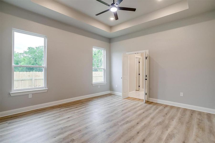 Spare room with baseboards, ceiling fan, light wood-type flooring, recessed lighting, and a raised ceiling Spare room with baseboards, ceiling fan, light wood-type flooring, recessed lighting, and a raised ceiling