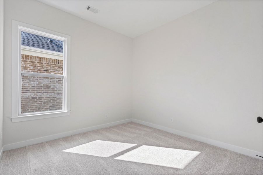 Light-toned wall paint, carpet flooring, a single window, and a black door handle