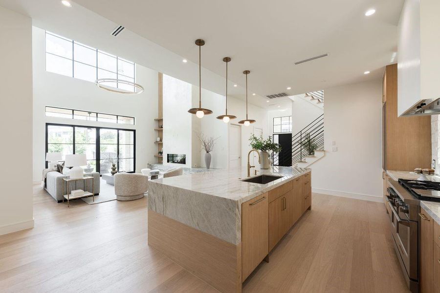 At the center of the home, a waterfall quartzite island anchors a living space defined by natural light, refined materials, and effortless flow. From morning coffee beneath the pendant lights to evenings gathered by the fireplace, the design balances grand scale with a feeling of calm and connection.