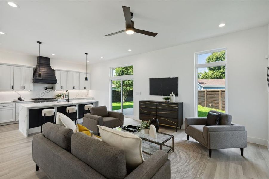 Living room with ceiling fan, light wood-type flooring, and sink