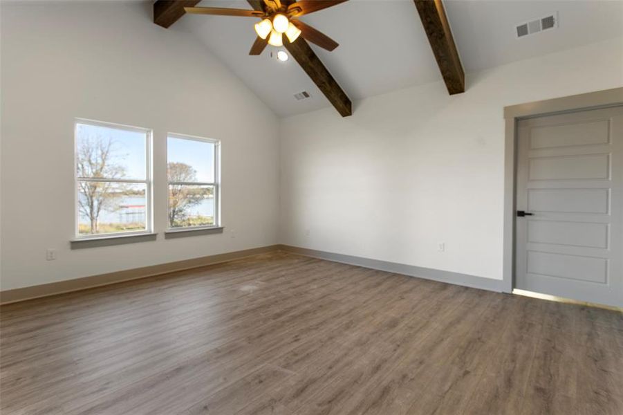 Spare room featuring beamed ceiling, ceiling fan, wood-type flooring, and high vaulted ceiling