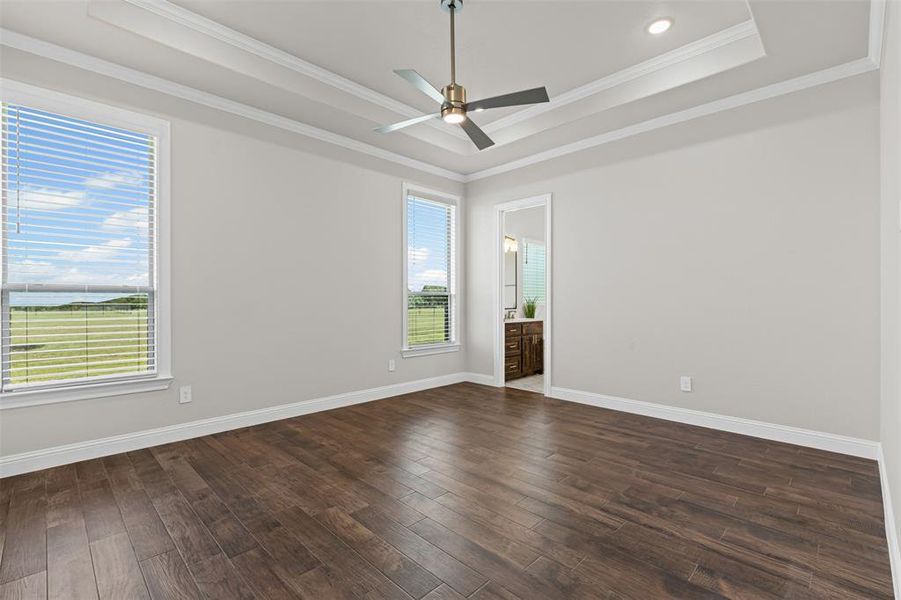 Primary Bedroom featuring a tray ceiling, dark wood finished floors, ornamental molding, ceiling fan, and recessed lighting Primary Bedroom featuring a tray ceiling, dark wood finished floors, ornamental molding, ceiling fan, and recessed lighting