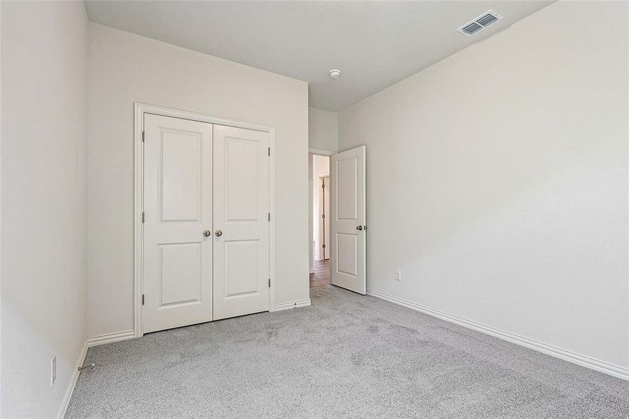 Unfurnished bedroom featuring light carpet and a closet