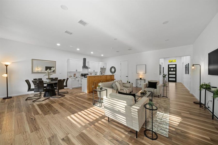 Kitchen with decorative backsplash, light hardwood / wood-style flooring, a kitchen island with sink, wall chimney exhaust hood, and range