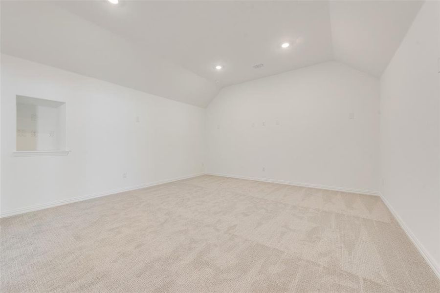 Spare room with light colored carpet and vaulted ceiling