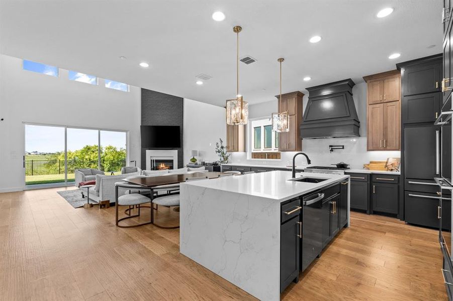 Kitchen with light stone countertops, hanging light fixtures, light wood-type flooring, open floor plan, and recessed lighting Kitchen with light stone countertops, hanging light fixtures, light wood-type flooring, open floor plan, and recessed lighting