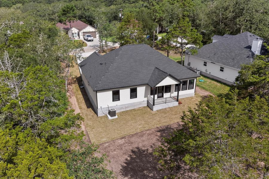 Nestled among green trees, this appealing residence presents a welcoming facade with a covered porch.
