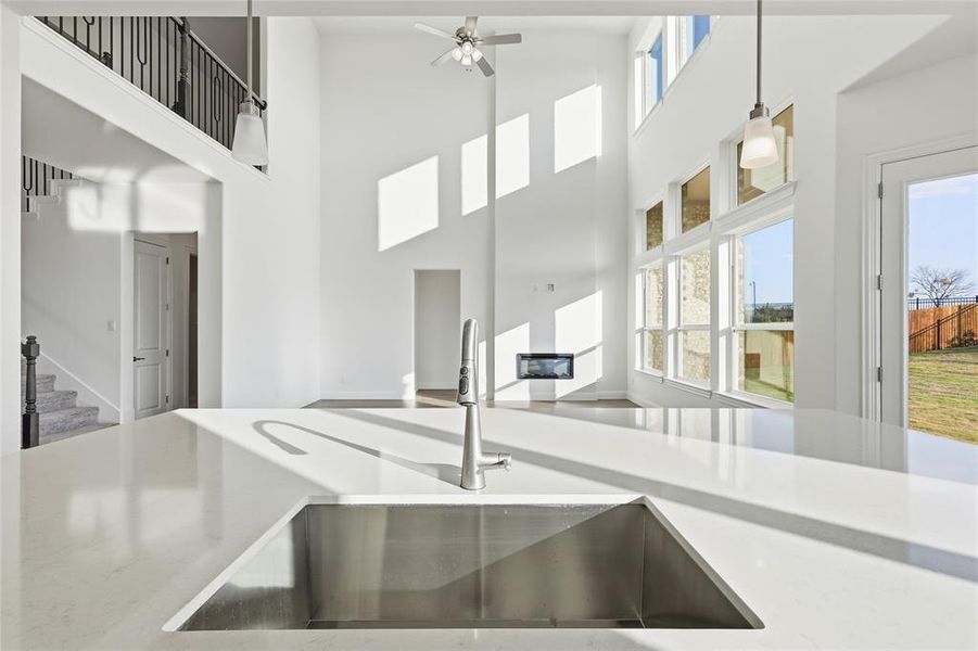 Kitchen with light stone counters, a high ceiling, a ceiling fan, decorative light fixtures, and open floor plan Kitchen with light stone counters, a high ceiling, a ceiling fan, decorative light fixtures, and open floor plan