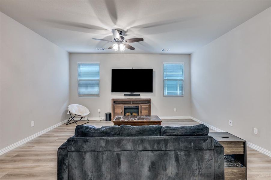 Living room with plenty of natural light, a fireplace, light wood-style floors, and ceiling fan