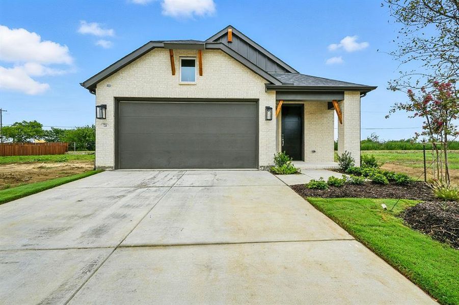 View of front of house featuring concrete driveway, brick siding, board and batten siding, and a porch View of front of house featuring concrete driveway, brick siding, board and batten siding, and a porch