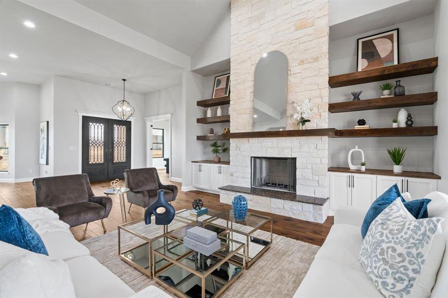 Living room with high vaulted ceiling, a fireplace, hardwood / wood-style floors, and a notable chandelier