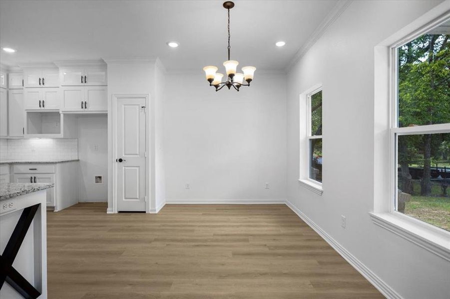 Unfurnished dining area featuring light wood-type flooring, a chandelier, crown molding, and recessed lighting
