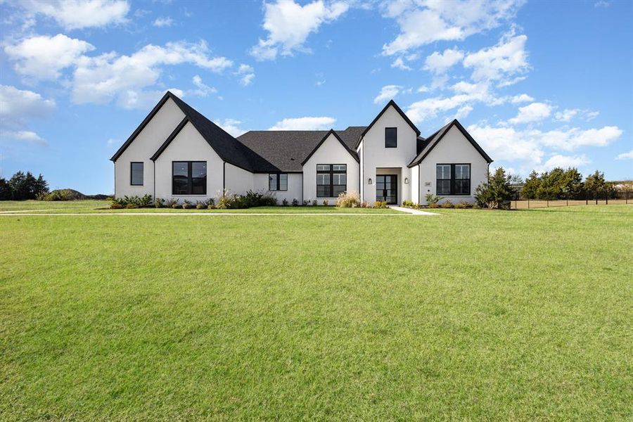 Modern inspired farmhouse featuring a front lawn and stucco siding