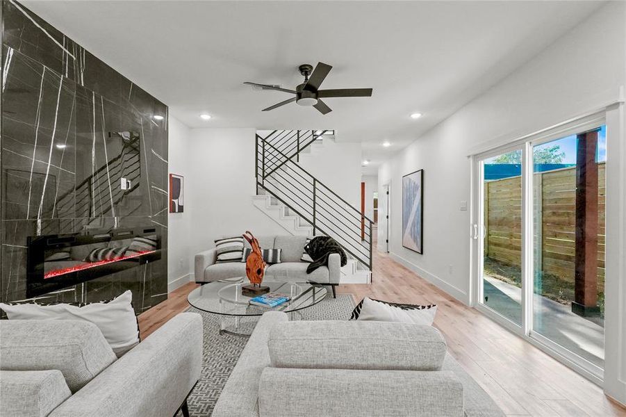 Living room with ceiling fan, light hardwood / wood-style flooring, and a fireplace