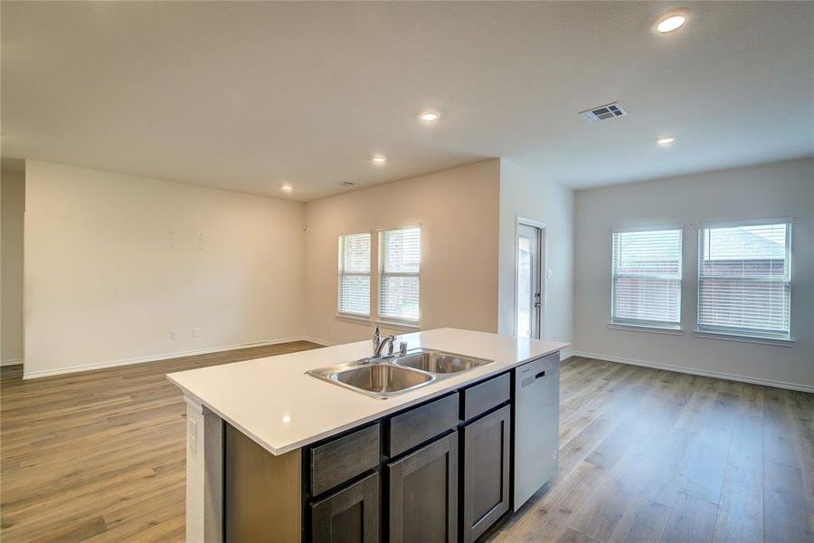 Kitchen featuring open floor plan, light countertops, a center island with sink, light wood-style floors, and recessed lighting