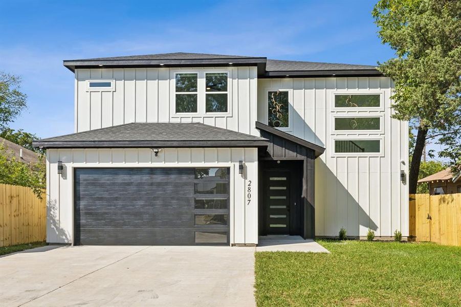 View of front of property featuring a front lawn and a garage