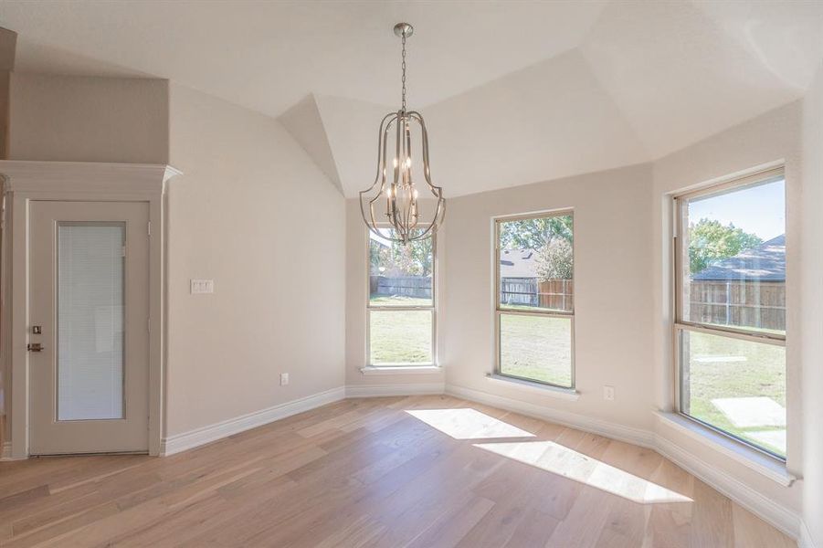 Unfurnished dining area featuring light hardwood / wood-style floors, a wealth of natural light, and a notable chandelier