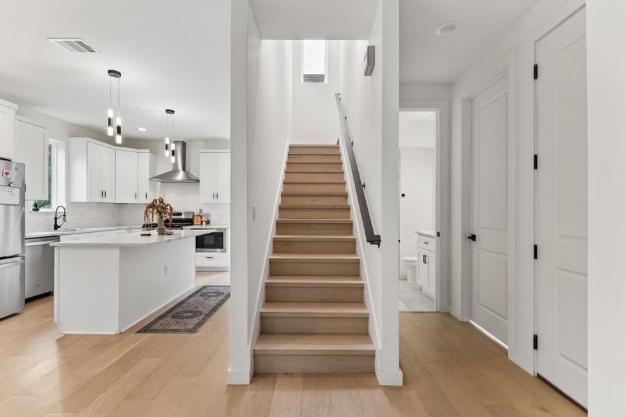 A view of the staircase, featuring modern metal railings and light wood treads. The design is open and sculptural, contributing to the home's contemporary architectural feel.