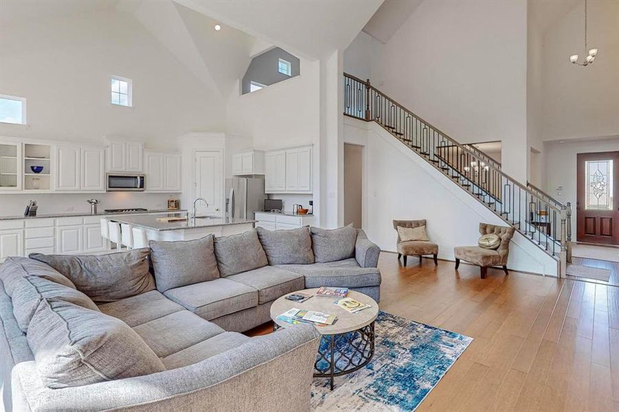 View of Living Room as you exit the Primary Bedroom. Staircase and entry are both visible with Dining area just on the other side of stairs. This space would be great for entertaining and can accommodate plenty of guests.