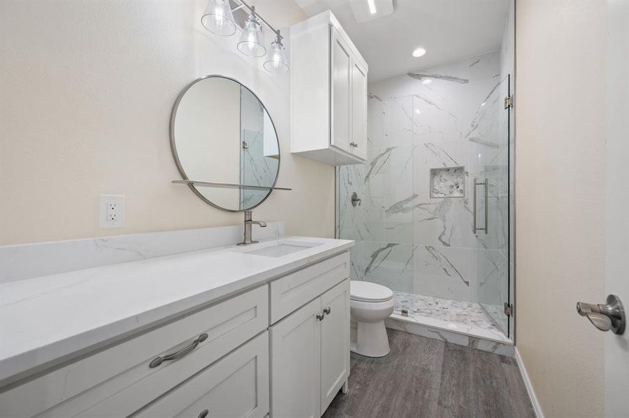 Full bathroom with vanity, a marble finish shower, and dark wood finished floors Full bathroom with vanity, a marble finish shower, and dark wood finished floors