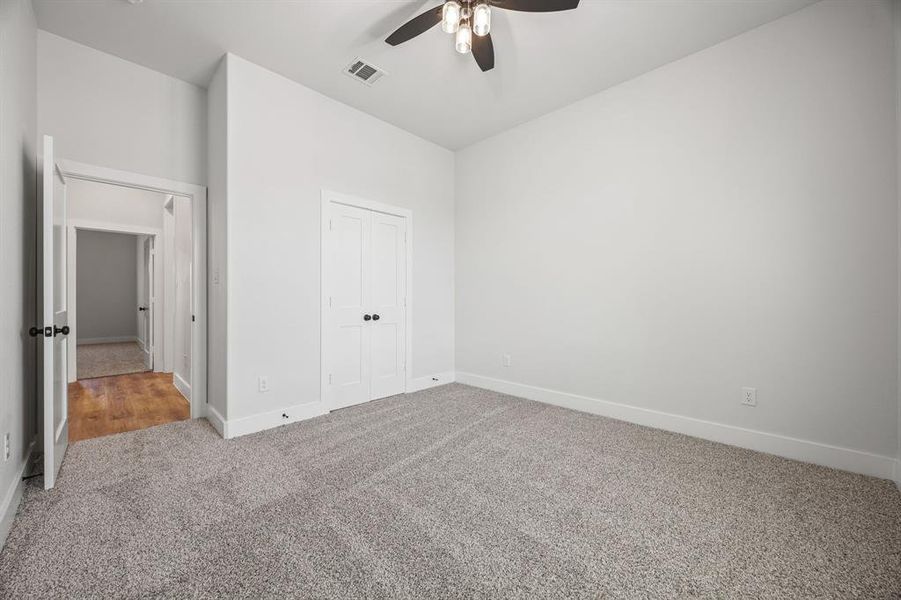 Unfurnished bedroom with carpet, a closet, and a ceiling fan Unfurnished bedroom with carpet, a closet, and a ceiling fan