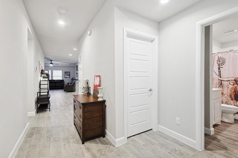 Hallway with light wood finished floors, baseboards, and recessed lighting