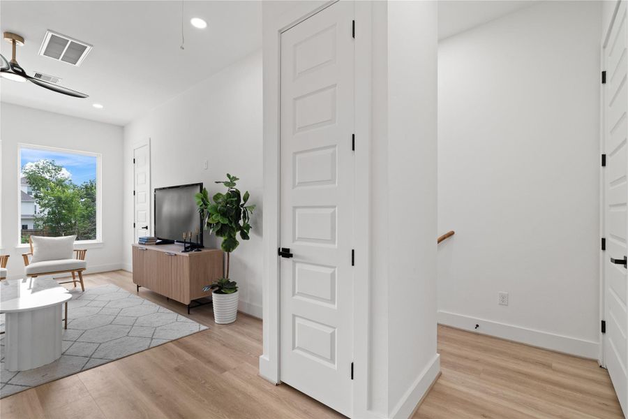 The top of the staircase opens toa spacious landing, framed byhigh ceilings and oversizedpicture windows that maximizenatural light. Shaker-style doorsconceal ample storage,maintaining a clean andcohesive architectural aesthetic.