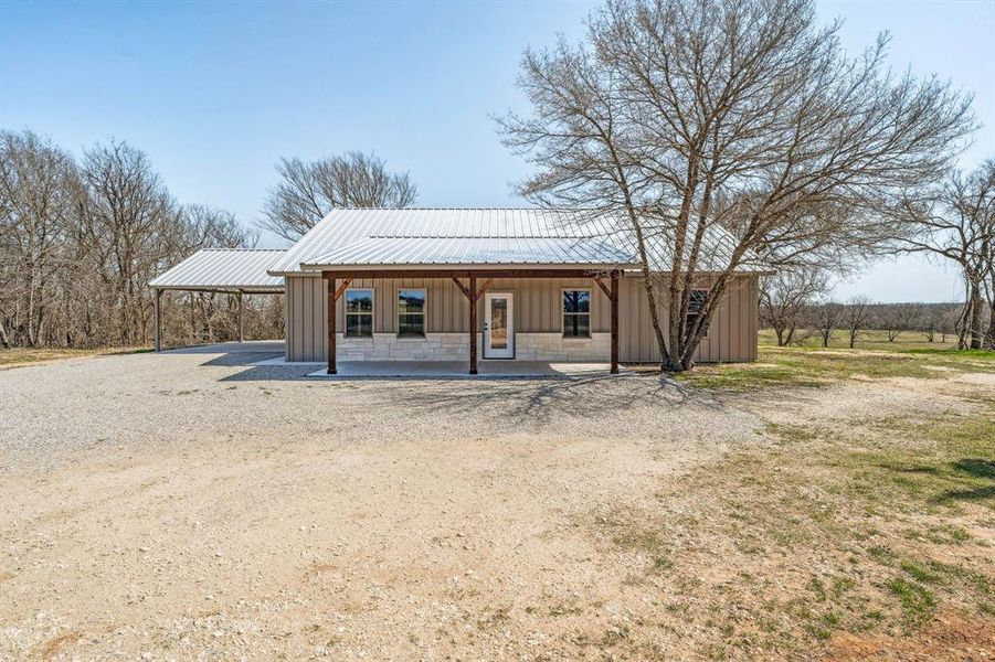 View of outdoor structure featuring an attached carport and gravel driveway
