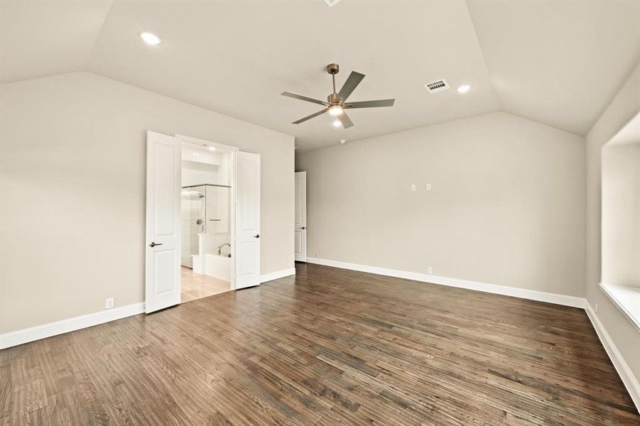 Unfurnished bedroom with lofted ceiling, wood finished floors, a ceiling fan, recessed lighting, and ensuite bath