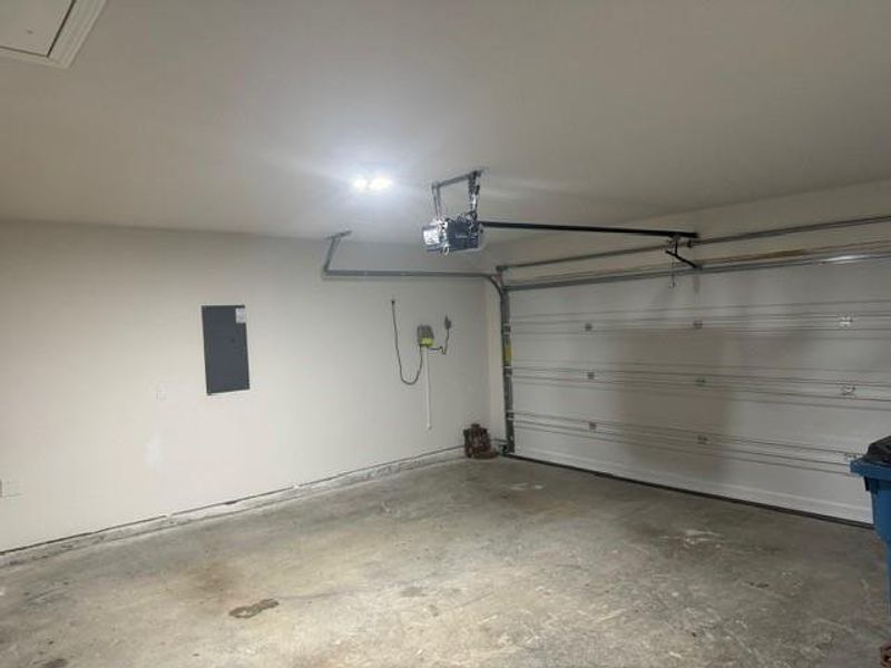 Garage featuring a garage door opener and electric panel