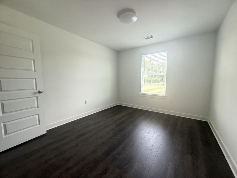 Spare room featuring dark wood finished floors and baseboards