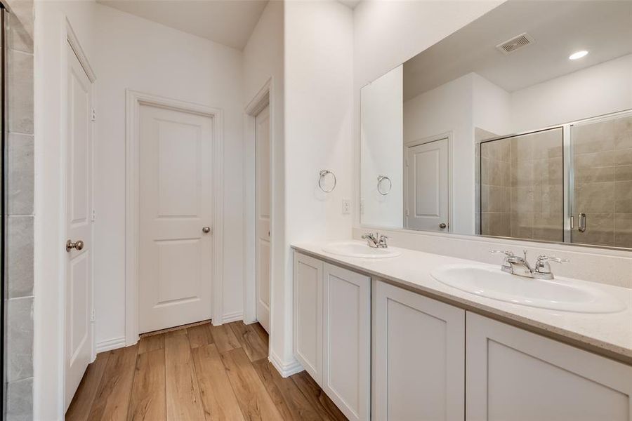 Bathroom featuring hardwood / wood-style floors, double sink vanity, and an enclosed shower