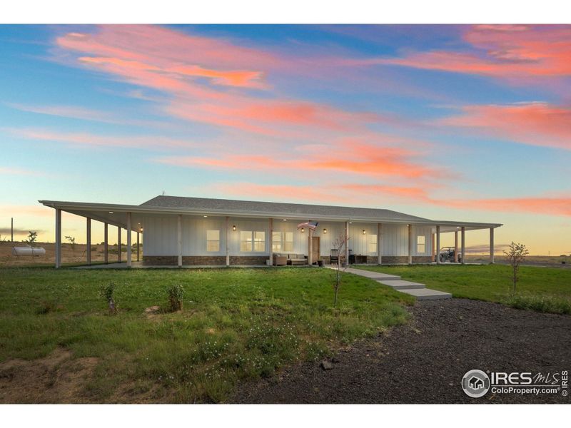 Beautiful country home with a wide wrap-around porch, stone accents, and warm exterior lighting. The spacious front patio offers the perfect spot to relax and enjoy the peaceful surroundings.