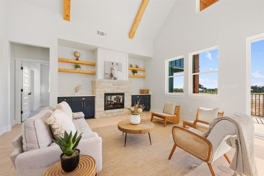 Living area featuring high vaulted ceiling, a fireplace, beamed ceiling, and light wood-style floors