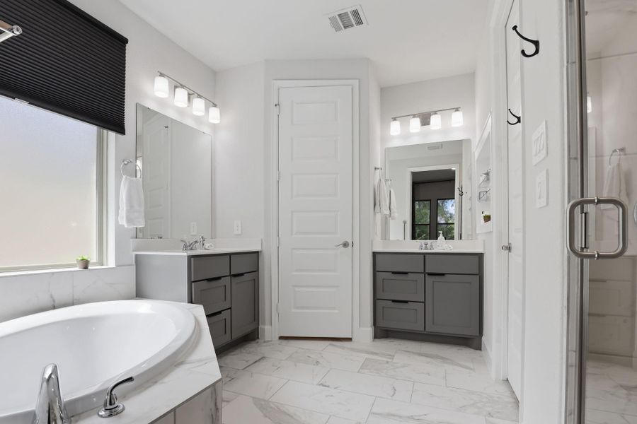The primary bath features a large glass-enclosed walk-in shower and a deep soaking tub.