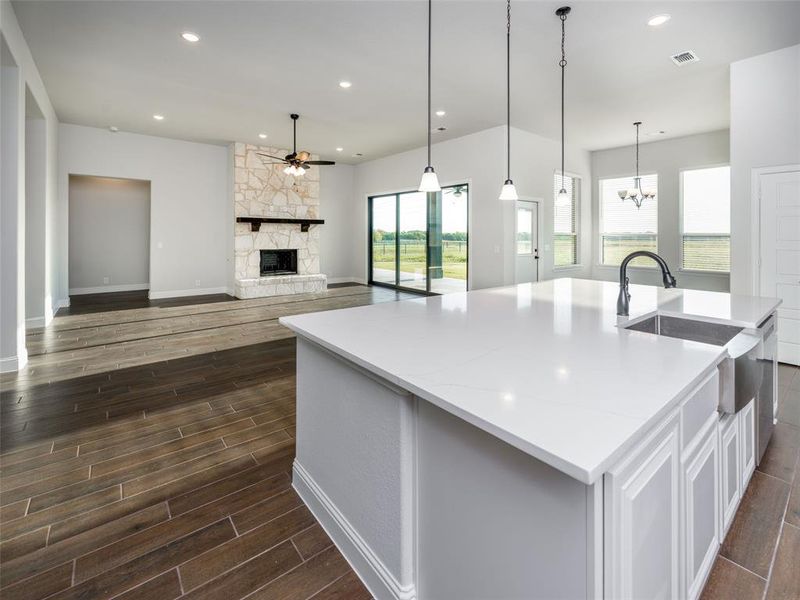 Kitchen featuring a fireplace, a large island with sink, recessed lighting, wood tiled floors, and open floor plan
