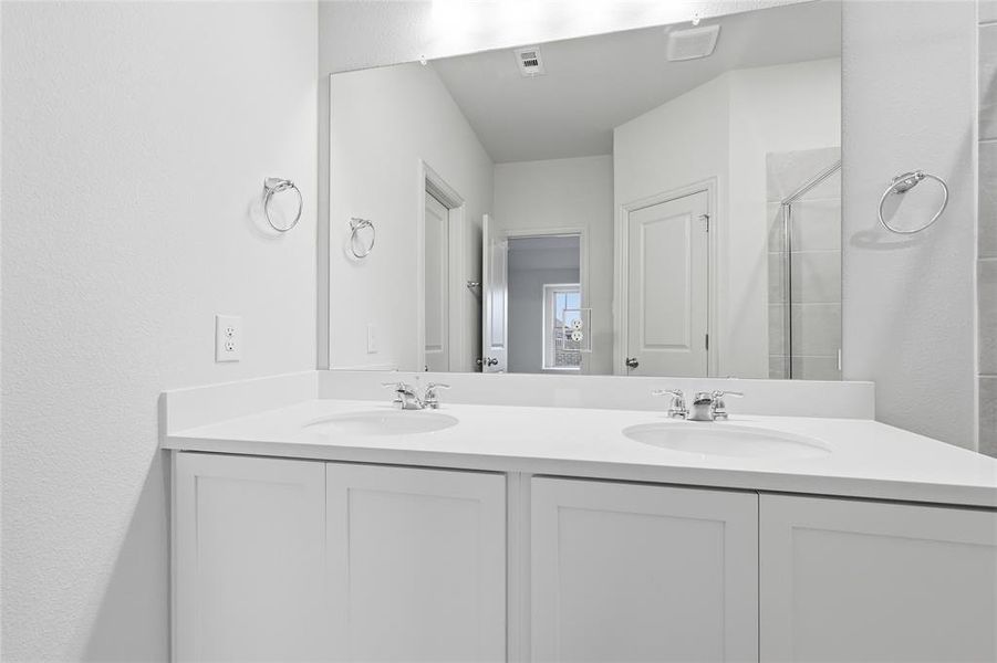 Full bath with double vanity and a stall shower